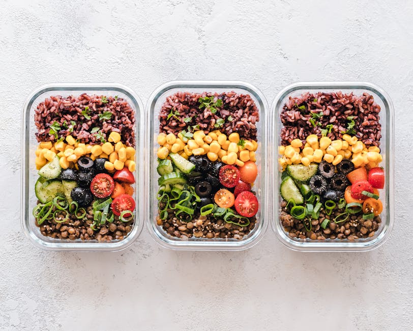 Colorful healthy meal prep with corn, olives, tomatoes, and lentils in glass containers